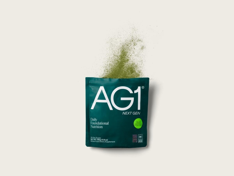 AG1 Next Gen Daily Foundational Nutrition 30-day supply pouch open with green powder dispersing showing NSF Sport certification badge
